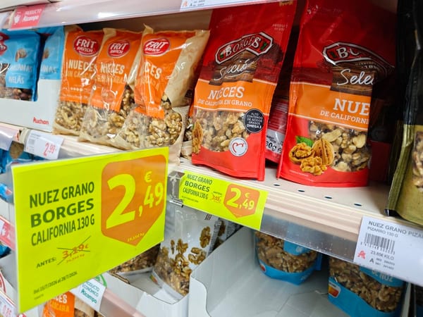Nueces de California en grano sobre una superficie de madera, con media nuez partida mostrando su interior